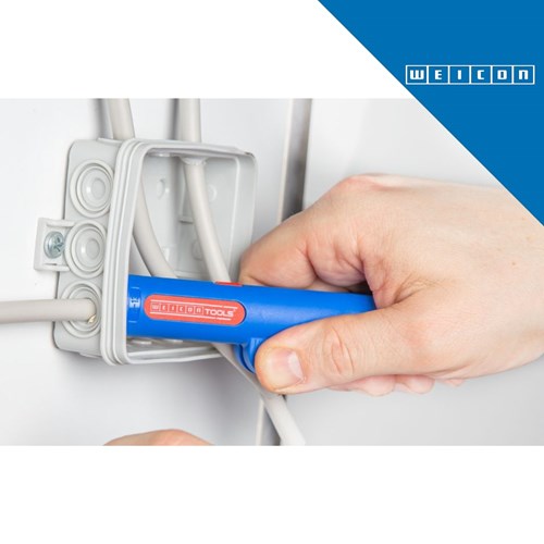 Ruka koristi plavi WEICONTOOL Round Cable Stripper No. 13 za skidanje izolacije s bijelog okruglog kabela u električnom ormariću.